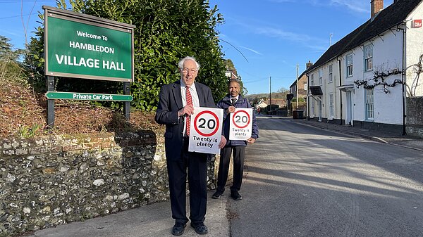 Two Liberal Democrat campaigners holding 20 is Plenty signs