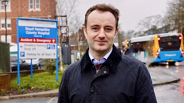 Danny Chambers standing in front of the Royal Hampshire County Hospital in Winchester. A sign for the A&E is in the background.